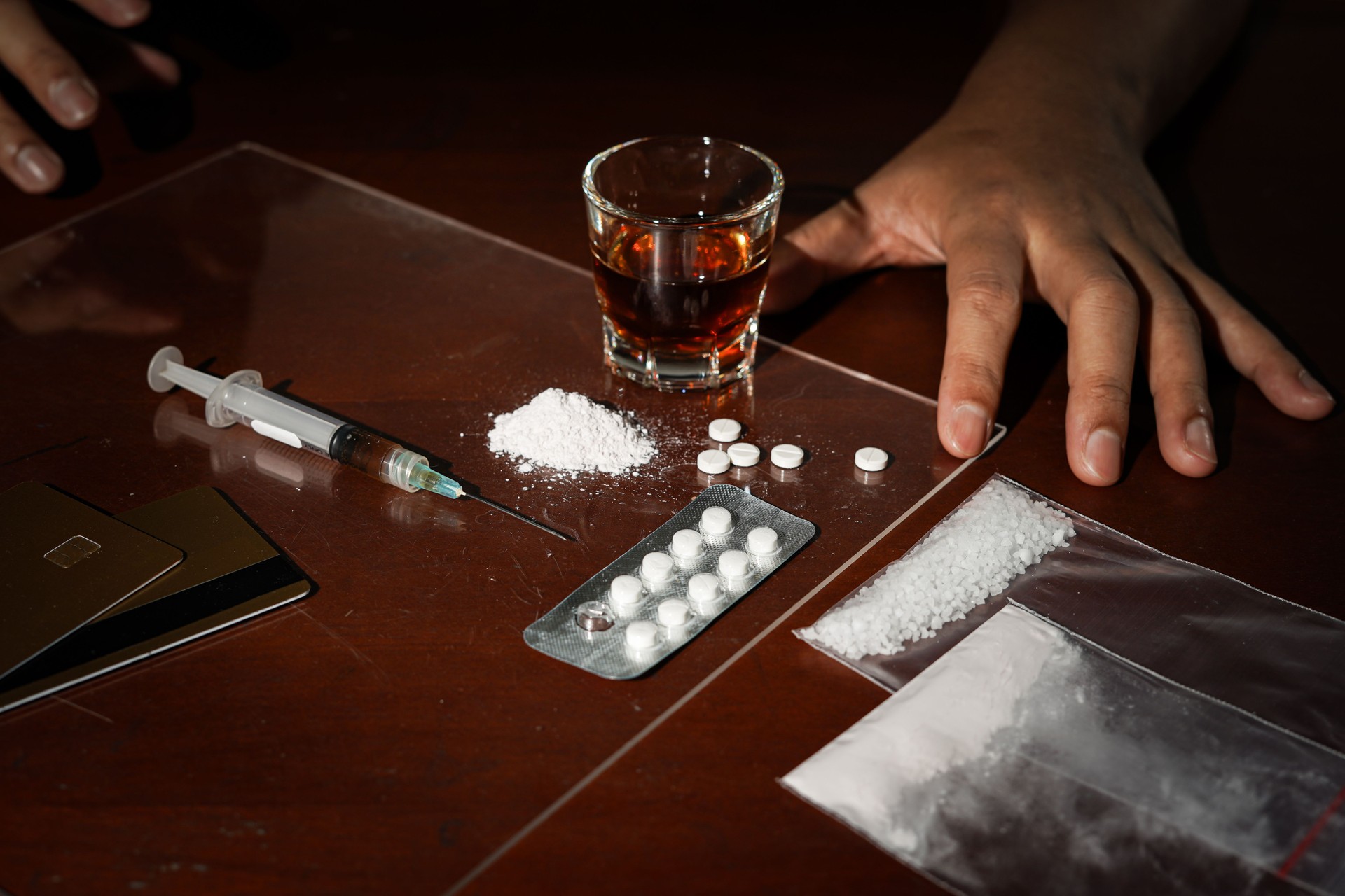 Drugs in the form of powder and tablets, a syringe on a dark background, drugs abuse